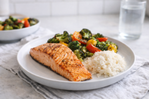 High-protein dinner plate with grilled salmon, roasted vegetables, and a small serving of rice for a weight loss-friendly meal
